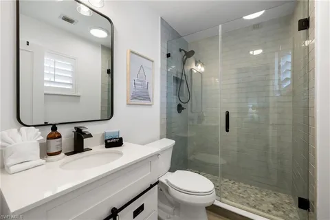 a bathroom with a sink a toilet a mirror and shower
