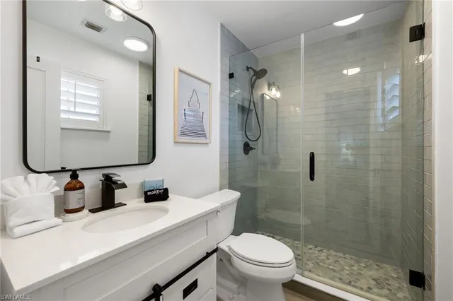 a bathroom with a sink a toilet a mirror and shower