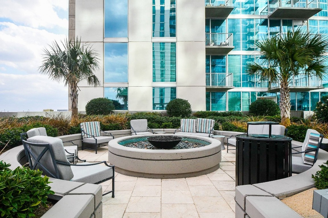 5925 Almeda Road, Unit 10704 Houston, TX 77004 - Photo 23 of 25 Outdoor fire pit lounge surrounded by lush landscaping and palm trees offers a comfortable space to gather and enjoy the open air.