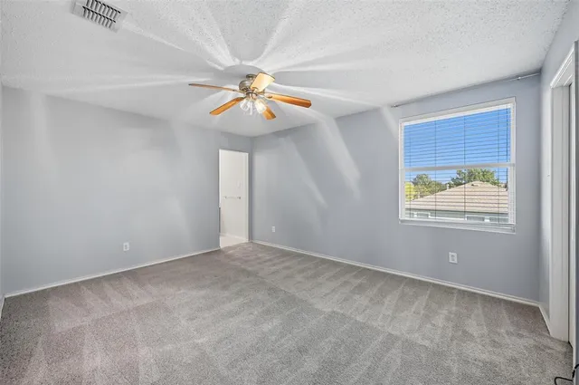 an empty room with windows and fan