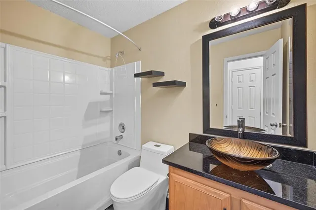 a bathroom with a granite countertop sink toilet a mirror and shower