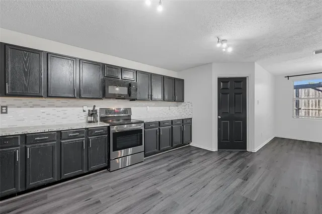 a large kitchen with wooden floors and stainless steel appliances