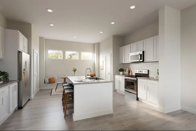 a kitchen with stainless steel appliances granite countertop a stove top oven a refrigerator a sink dishwasher and white cabinets with wooden floor