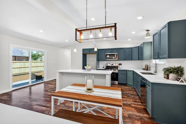 a large kitchen with kitchen island a large counter space a sink appliances and cabinets