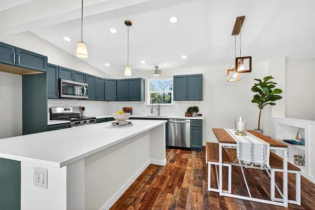 a open kitchen with kitchen island a sink stainless steel appliances and white cabinets