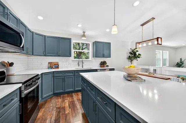 a kitchen with a sink a counter space and a view of living room