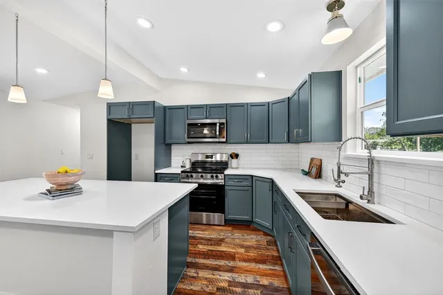 a view of a big room with wooden floor a ceiling fan and windows