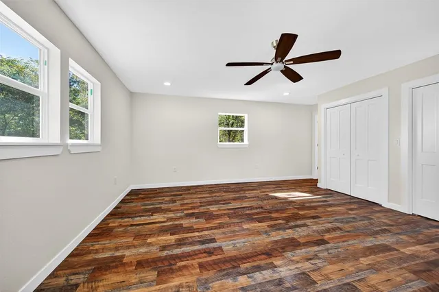 a view of a bedroom with wooden floor closet and windows