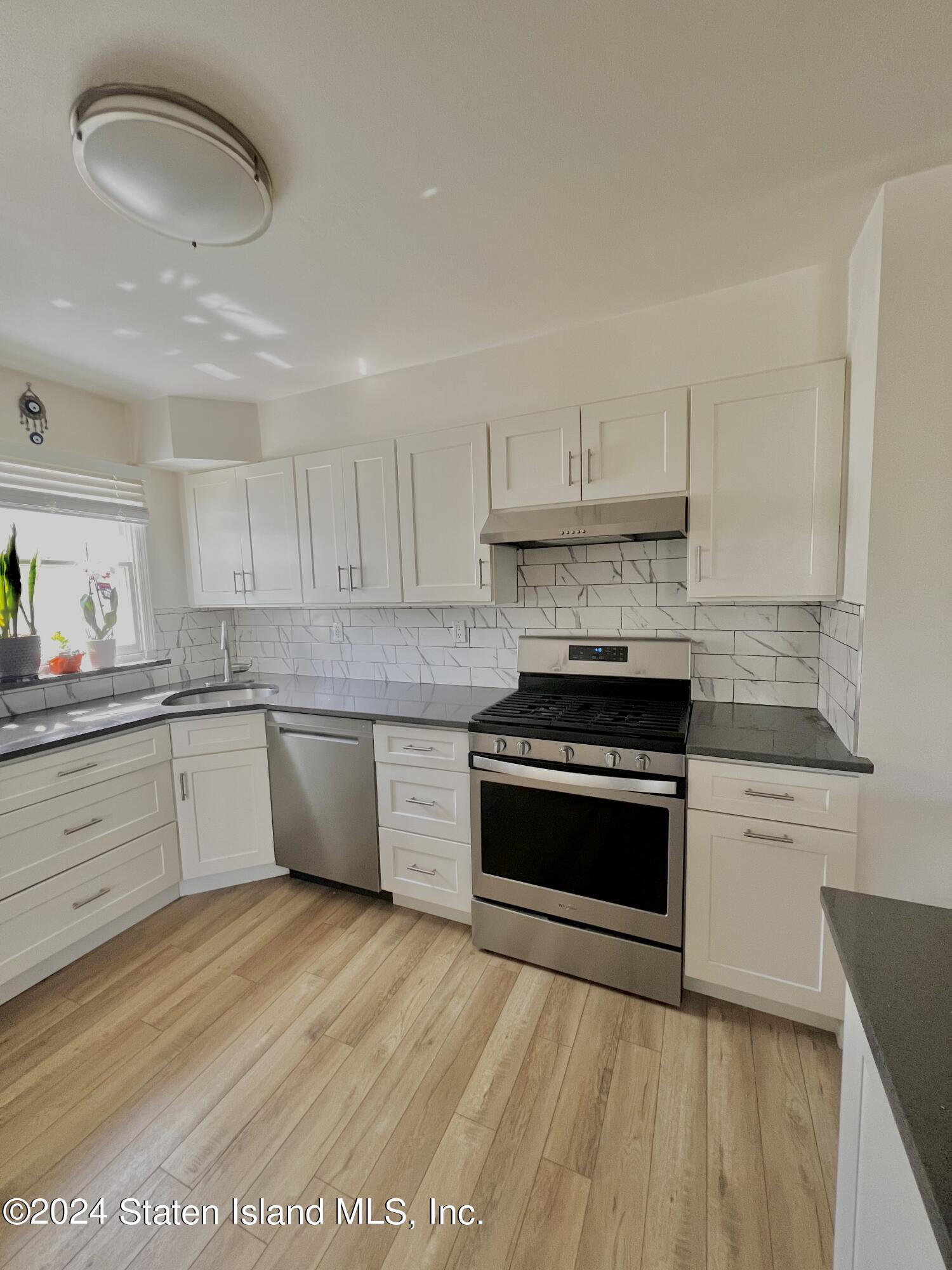 4 Futurity Place Staten Island, NY 10312 - Photo 11 of 26 a large kitchen with stainless steel appliances granite countertop a stove a sink and a white countertops with wooden floor