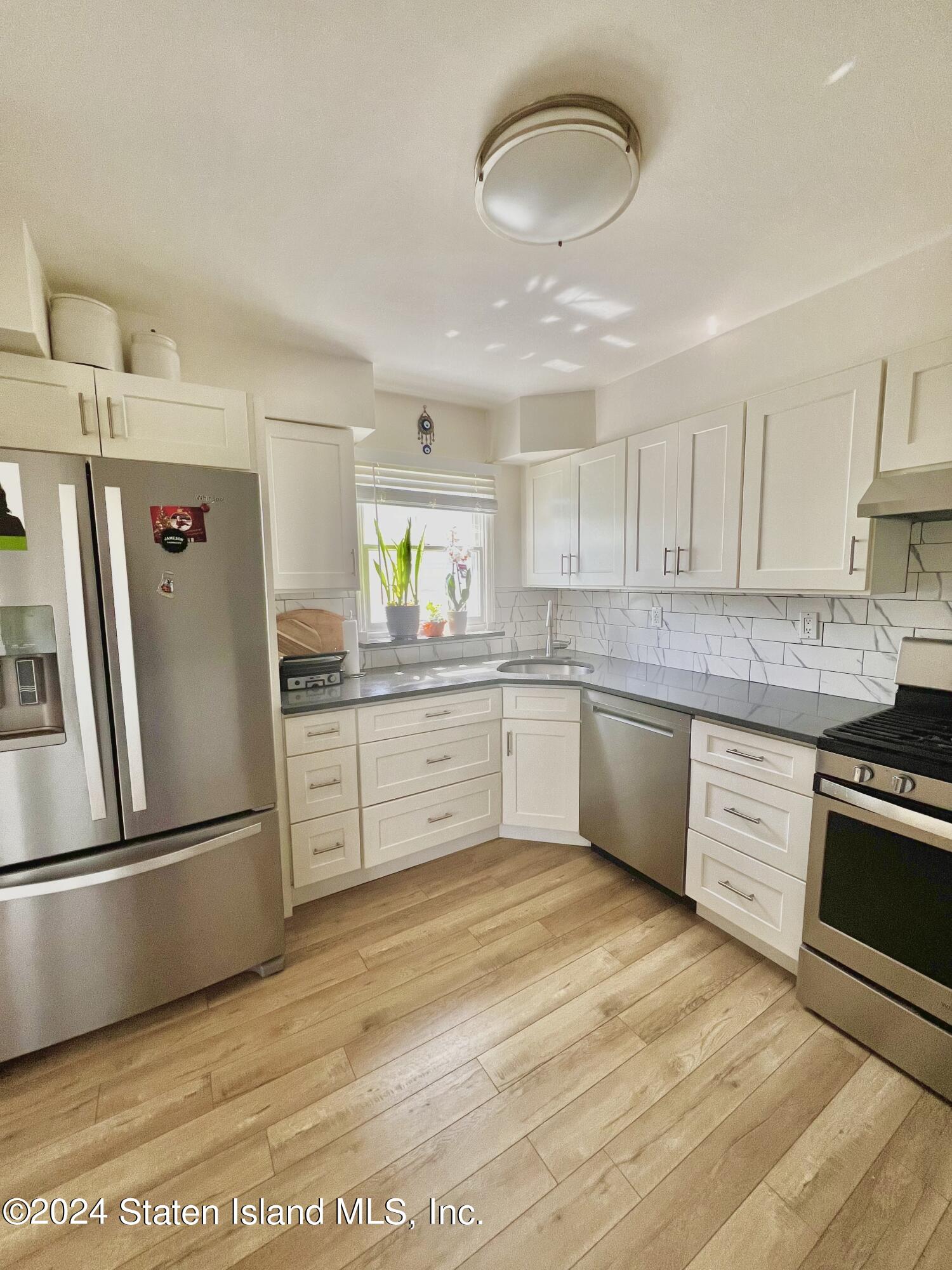 4 Futurity Place Staten Island, NY 10312 - Photo 12 of 26 a kitchen with stainless steel appliances granite countertop a sink dishwasher a refrigerator a microwave oven with cabinets and wooden floor