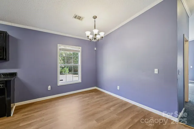 a kitchen with stainless steel appliances granite countertop a refrigerator a sink dishwasher a oven a dining table and chairs with wooden floor