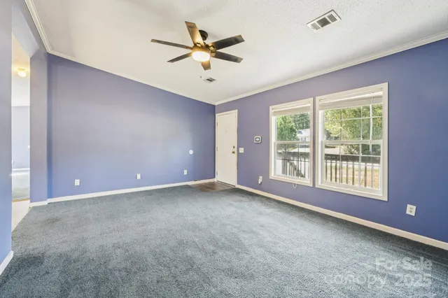 an empty room with windows and fan