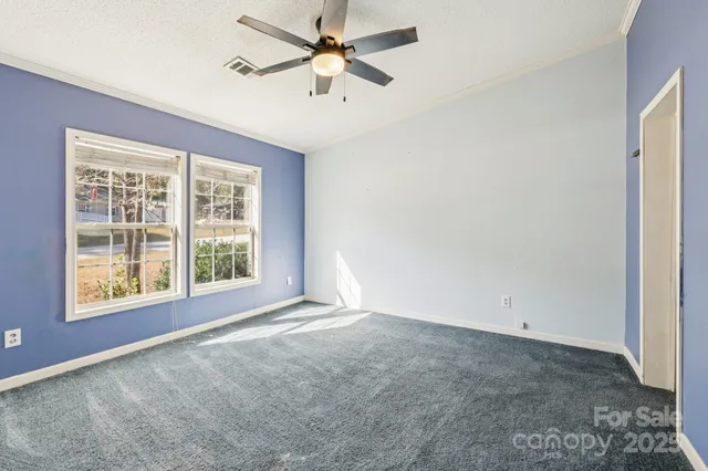 an empty room with a window and a fan