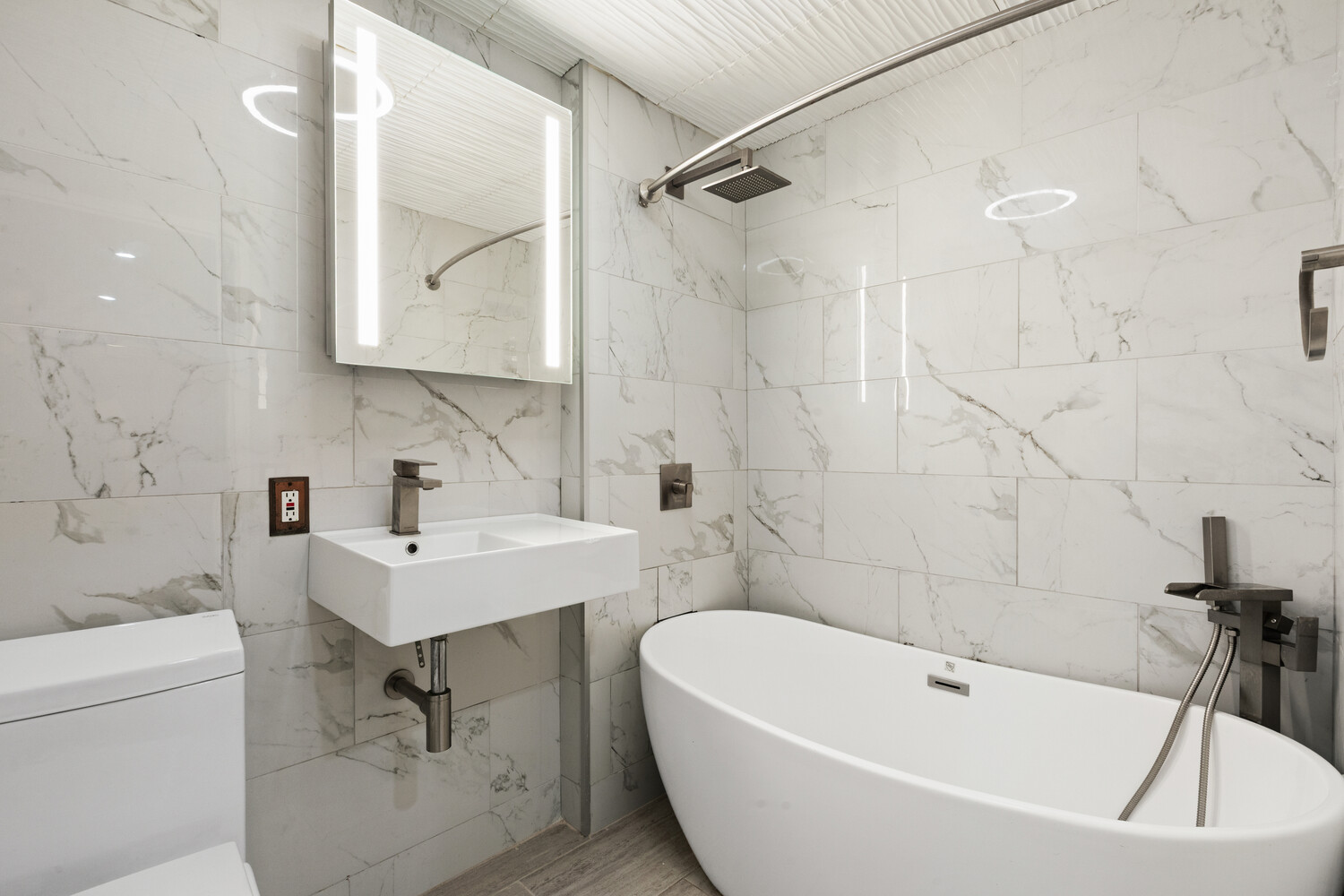 29 West 138th Street, Unit 2D Manhattan, NY 10037 - Photo 10 of 11 a white bath tub sitting next to a white sink and vanity