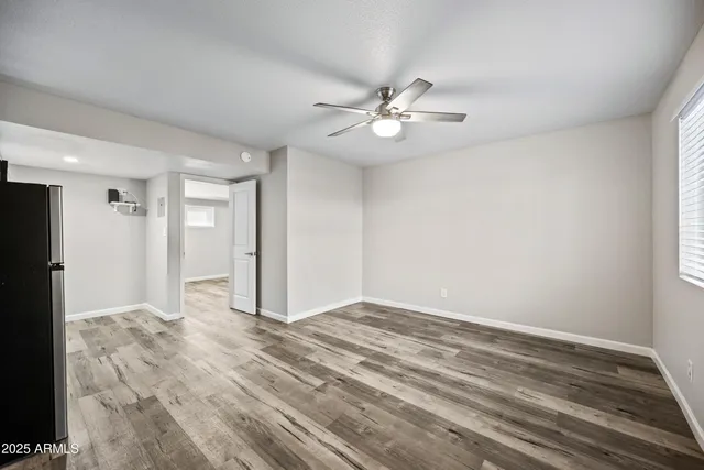 a view of empty room with wooden floor and ceiling fan
