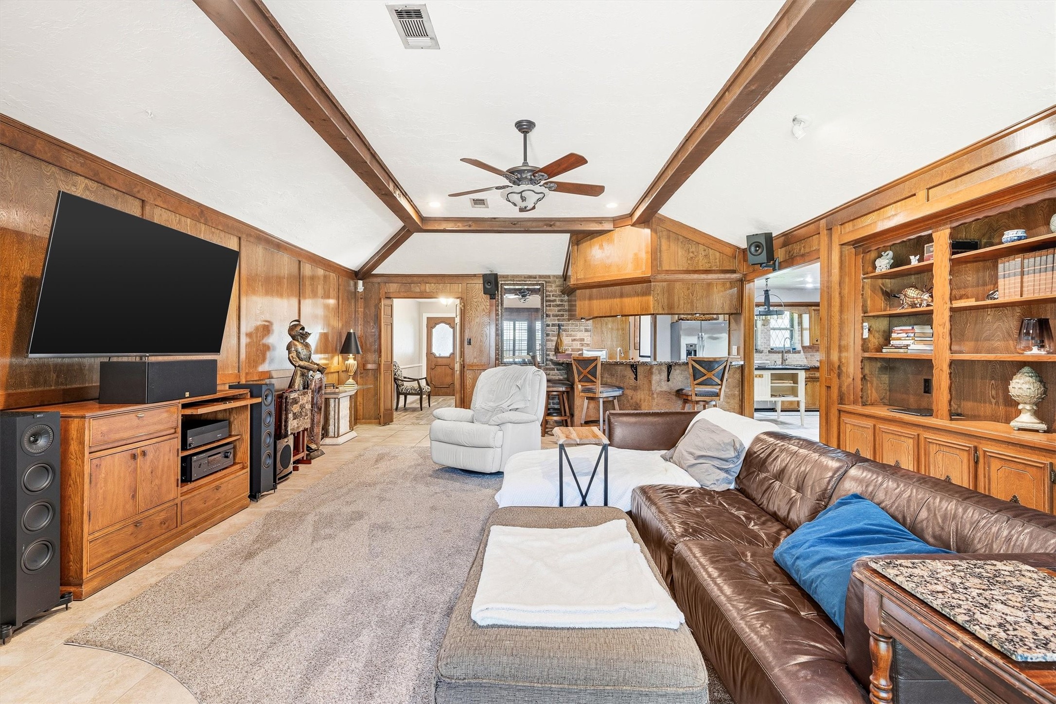 826 North Rivershire Drive Conroe, TX 77304 - Photo 8 of 46 rom this angle, the full scale of the living room opens up — vaulted beamed ceilings, built-in shelving, wood paneling, and a flow that connects seamlessly to the dining and kitchen beyond. There is no shortage of space to spread out here.