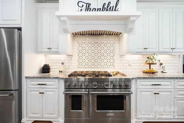 a kitchen with granite countertop a stove and a white refrigerator