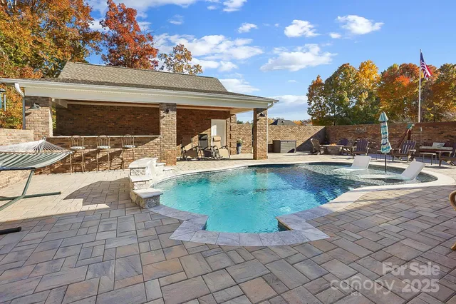 a view of a backyard with swimming pool and sitting area