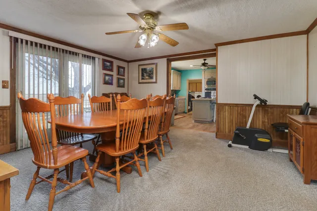 a dining room with furniture and a chandelier fan