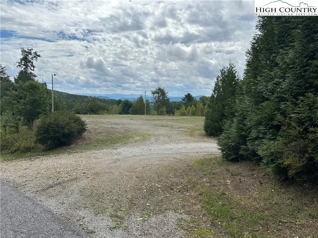 a view of dirt field with large trees