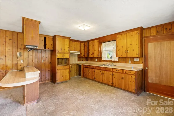 a large kitchen with granite countertop a sink refrigerator and cabinets