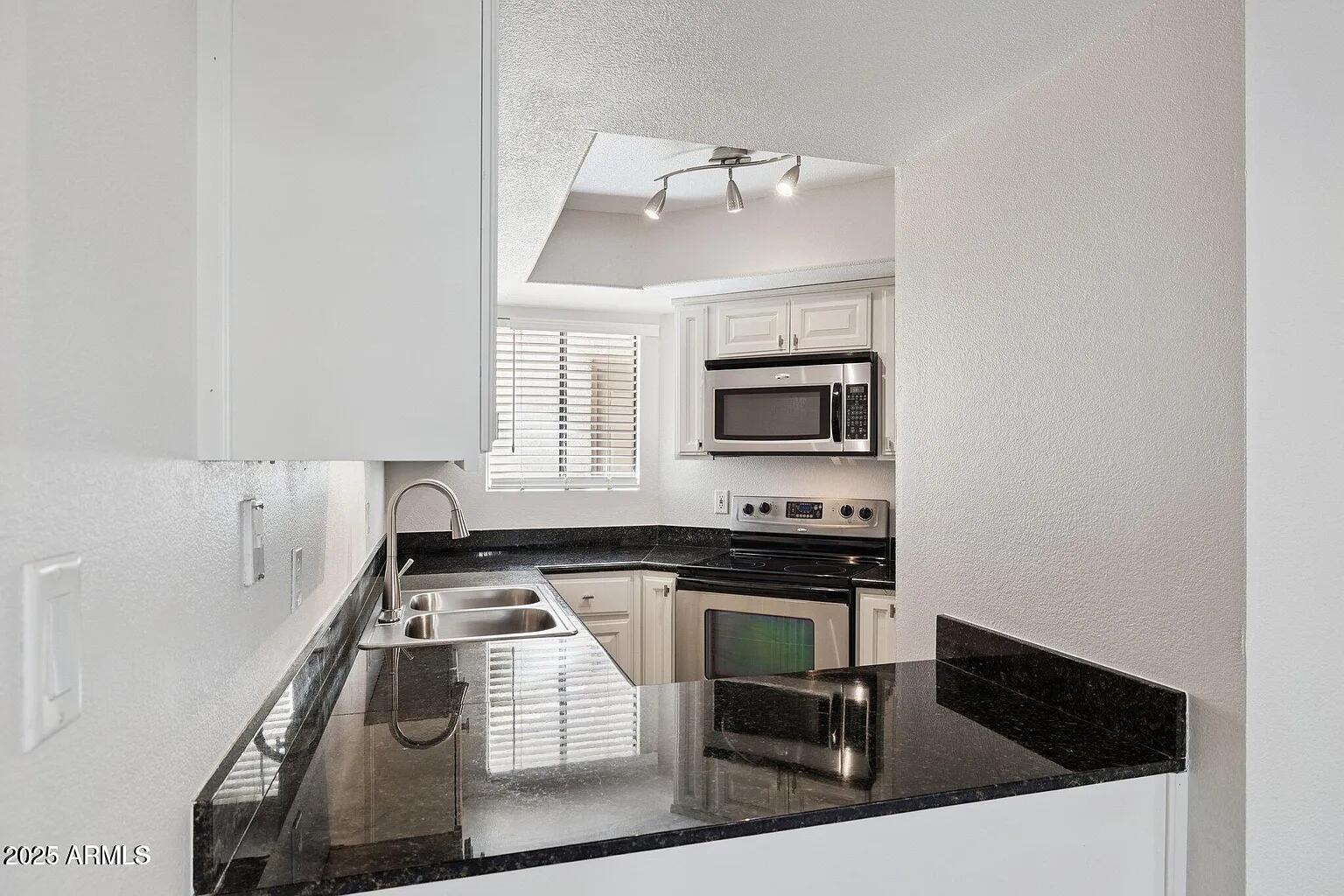 935 North Granite Reef Road, Unit 100 Scottsdale, AZ 85257 - Photo 8 of 29 a kitchen with a sink a stove and cabinets