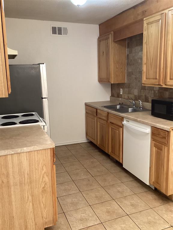 214 Locust Street South Sulphur Springs, TX 75482 - Photo 6 of 13 a kitchen with white cabinets a sink and white appliances