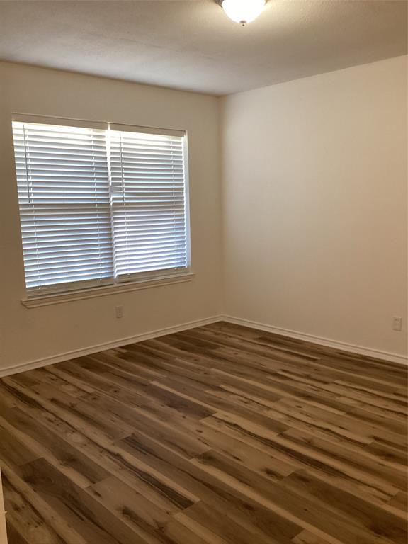 214 Locust Street South Sulphur Springs, TX 75482 - Photo 9 of 13 a view of an empty room with wooden floor and a window