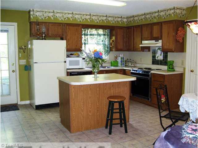 5615 Horse Farm Road Summerfield, NC 27358 - Photo 5 of 15 Kitchen. Kitchen offers an island (moveable) that provides additional storage plus counter seating! All appliances remain including the washer and dryer! Laundry room is located off the kitchen and offers additional storage.