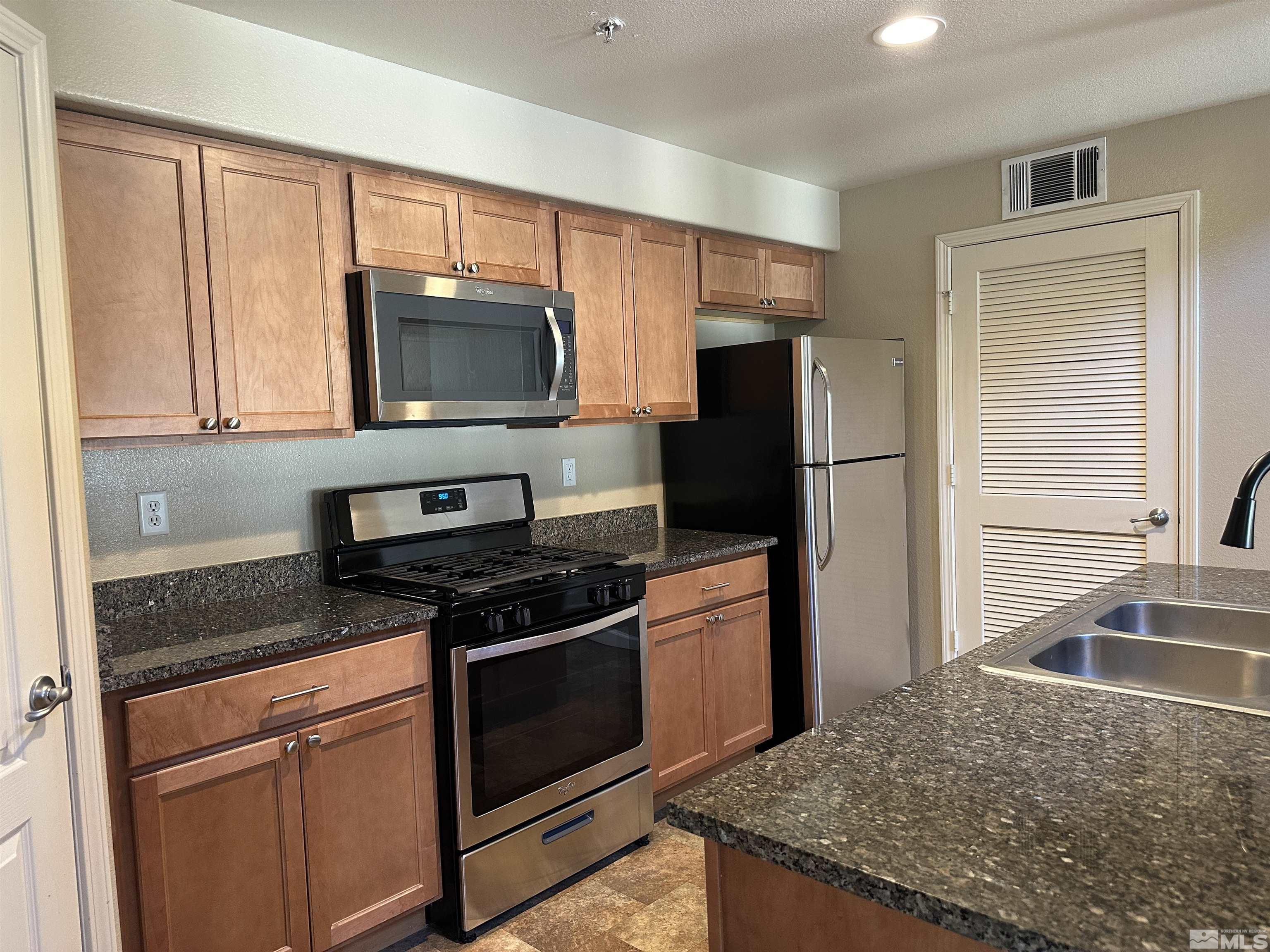 9050 Double R Boulevard, Unit 422 Reno, NV 89521 - Photo 7 of 33 a kitchen with granite countertop a stove and a sink