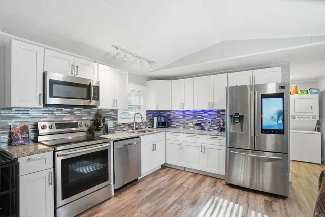 a kitchen with stainless steel appliances granite countertop a sink a stove a microwave and cabinets