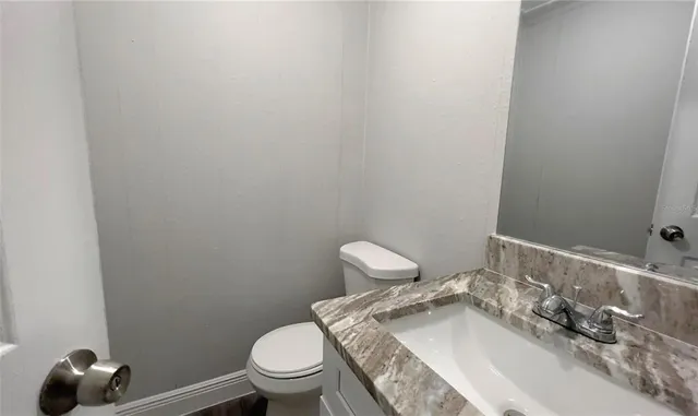 a bathroom with a granite countertop toilet and sink