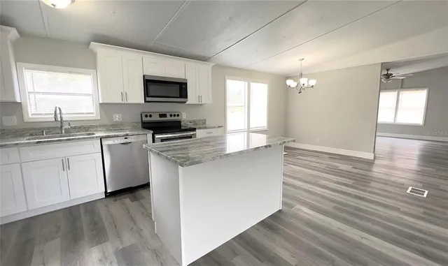 a kitchen with stainless steel appliances granite countertop a sink a stove top oven a counter space and cabinets