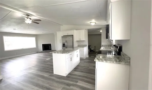 a large kitchen with kitchen island a large counter top space a sink stainless steel appliances and cabinets