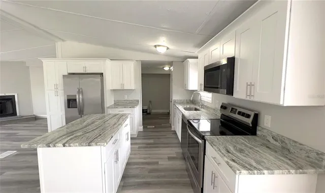 a kitchen with stainless steel appliances kitchen island granite countertop a stove and a sink