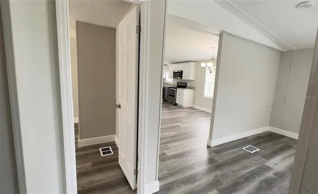 a view of a hallway with wooden floor and a living room