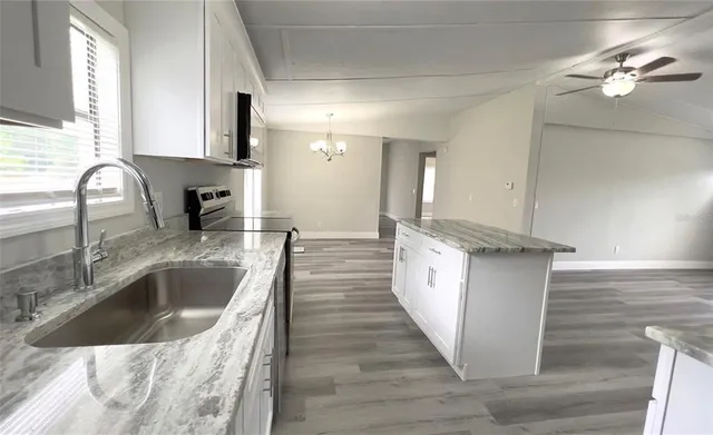 a kitchen with kitchen island granite countertop a sink and refrigerator