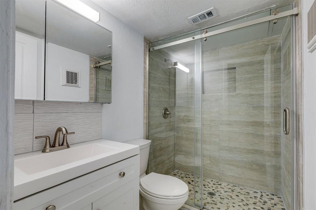 4606 Chaha Road, Unit 106 Garland, TX 75043 - Photo 9 of 22 Bathroom with vanity, tasteful backsplash, toilet, and walk in shower