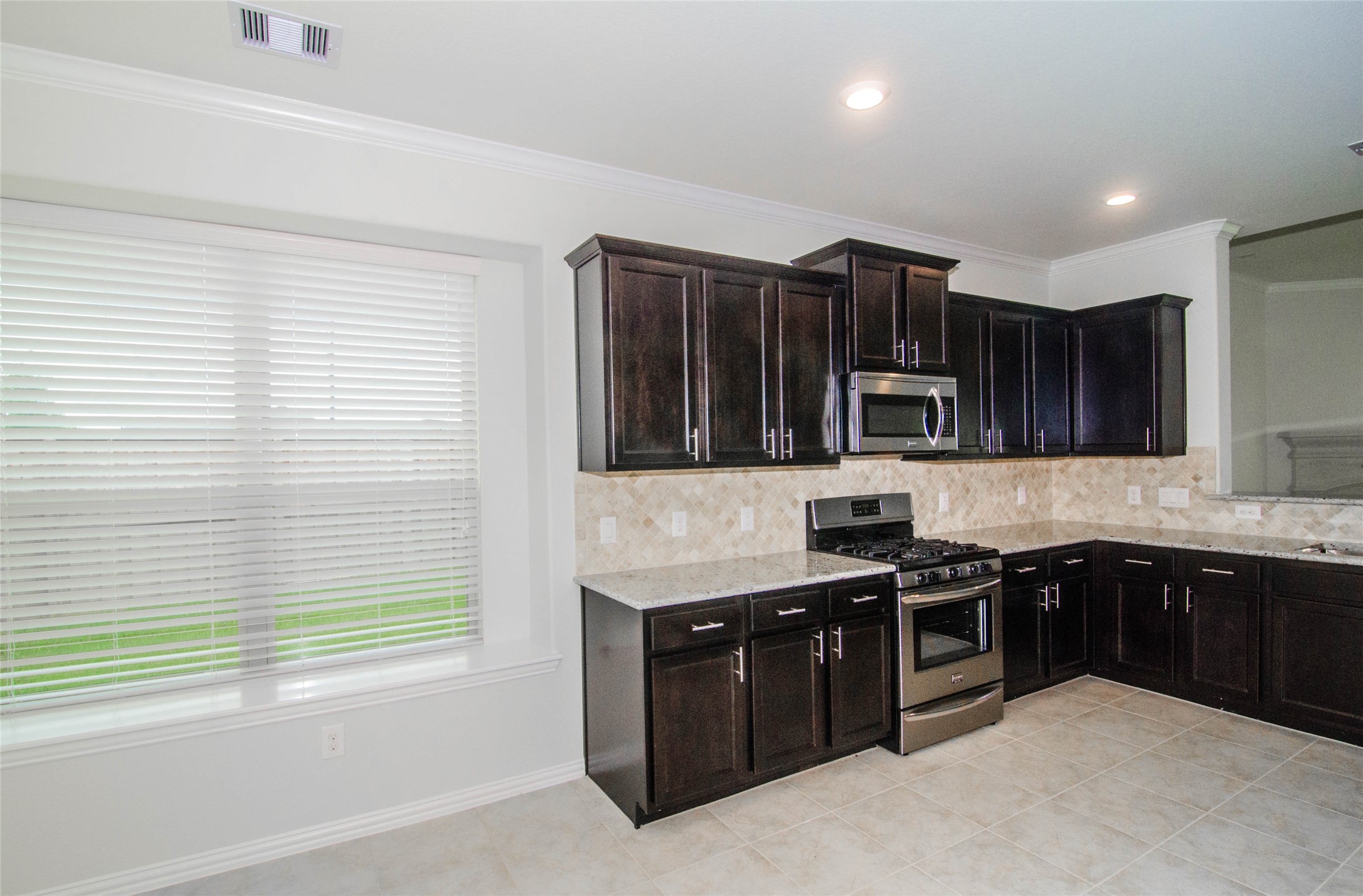 18403 Weeping Spring Drive Cypress, TX 77429 - Photo 7 of 25 a kitchen with stainless steel appliances granite countertop a stove a sink and a microwave