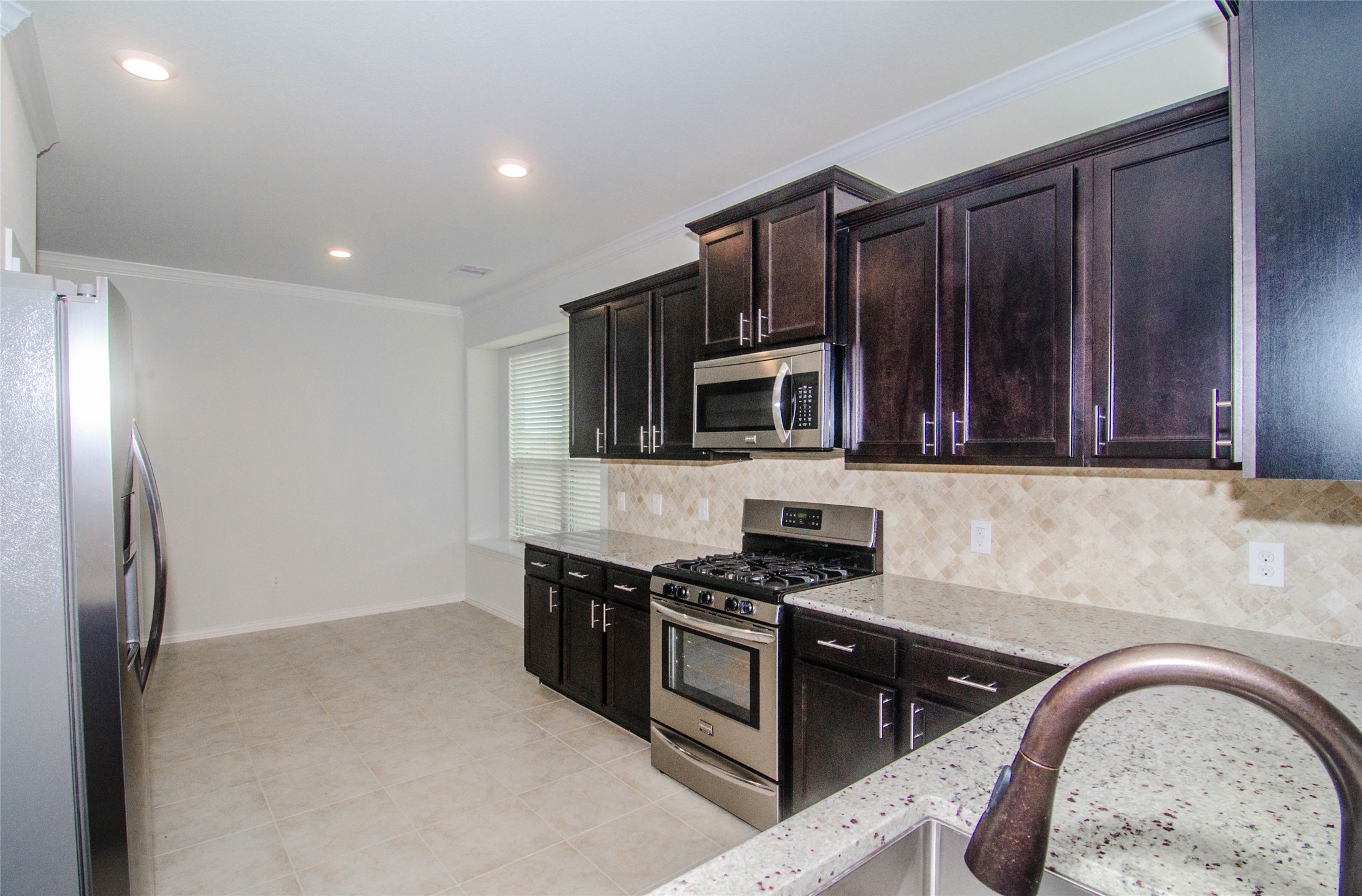 18403 Weeping Spring Drive Cypress, TX 77429 - Photo 8 of 25 a kitchen with stainless steel appliances granite countertop a stove a sink and a microwave