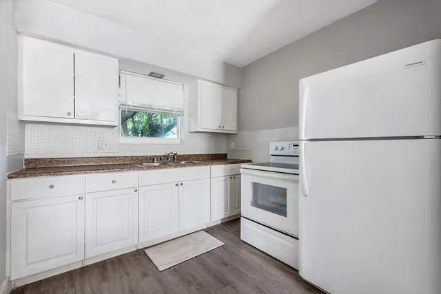 a kitchen with granite countertop white cabinets and white appliances
