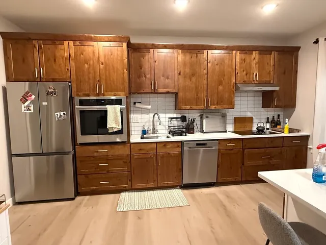 a kitchen with a refrigerator a stove a sink dishwasher and wooden cabinets