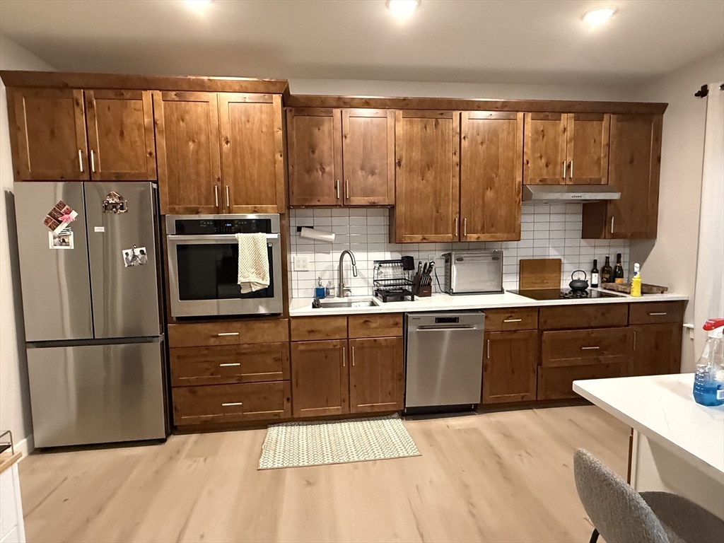a kitchen with a refrigerator a stove a sink dishwasher and wooden cabinets