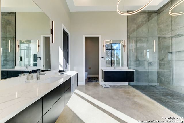 417 Southwick Ranch Johnson City, TX 78636 - Photo 17 of 45 a bathroom with a double vanity sink a large mirror and shower