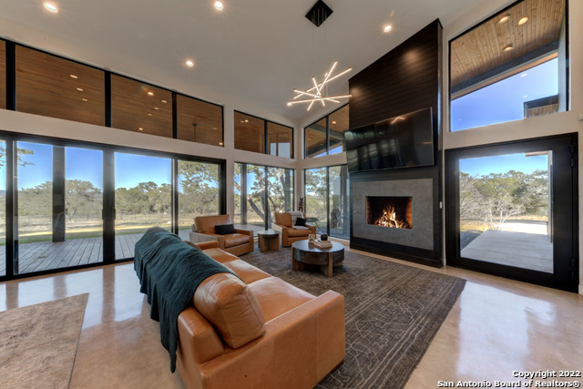 417 Southwick Ranch Johnson City, TX 78636 - Photo 4 of 45 a living room with furniture a fireplace and floor to ceiling window