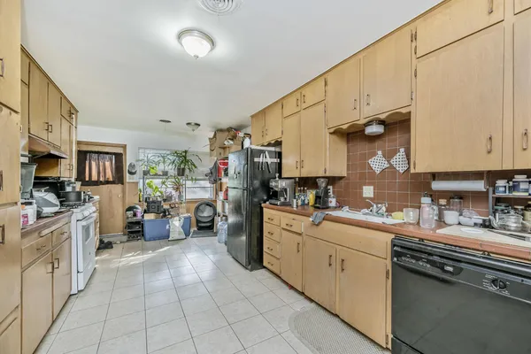 a kitchen with a sink dishwasher stove and white cabinets