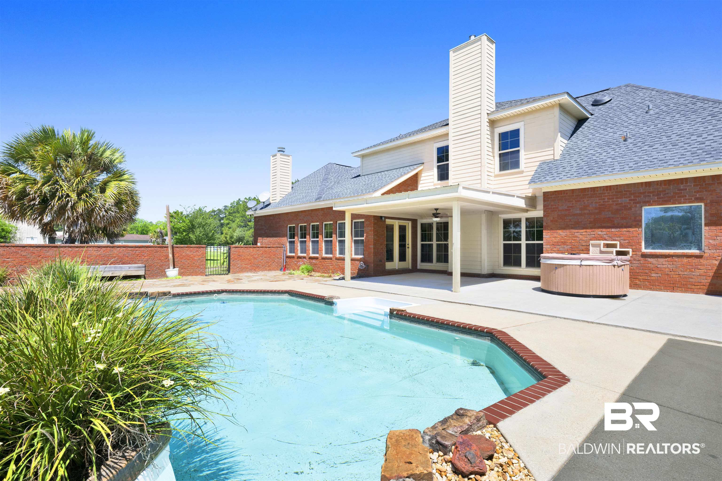 12944 Anna's Way Stapleton, AL 36578 - Photo 25 of 64 Rear exterior featuring a swimming pool, integrated spa, covered patio, brick and siding facade, and multiple windows