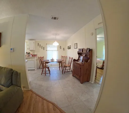 a living room with furniture and a dining table with wooden floor
