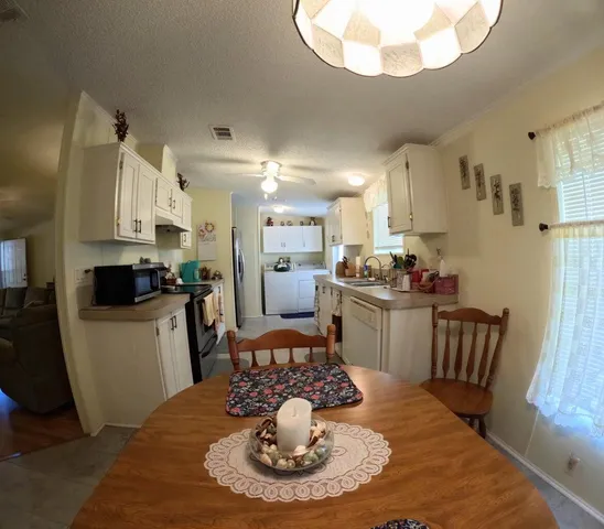 a kitchen with stainless steel appliances granite countertop a sink dishwasher a stove a refrigerator a dining table and chairs with wooden floor