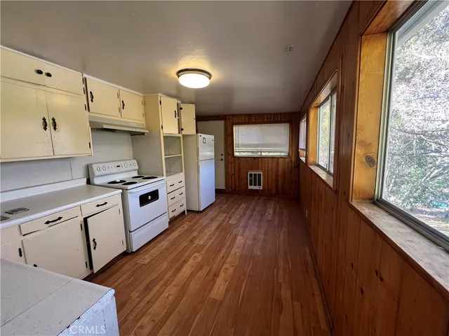 a kitchen with granite countertop a stove a sink a refrigerator and wooden floor